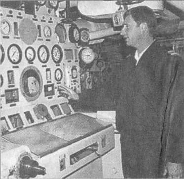 Disposal officer Lt.-Cmdr. Greg van der Krogt in engine room, explaining how the ship's boilers and machinery were monitored from this control panel